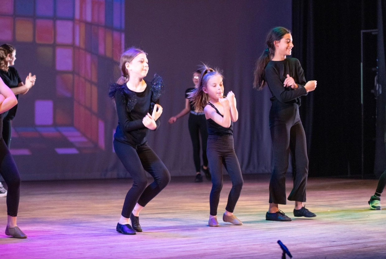 children dressed in black dancing on stage