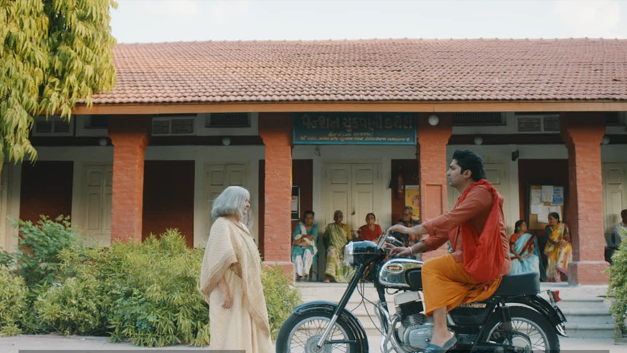 Person on motorbike outside building with people around