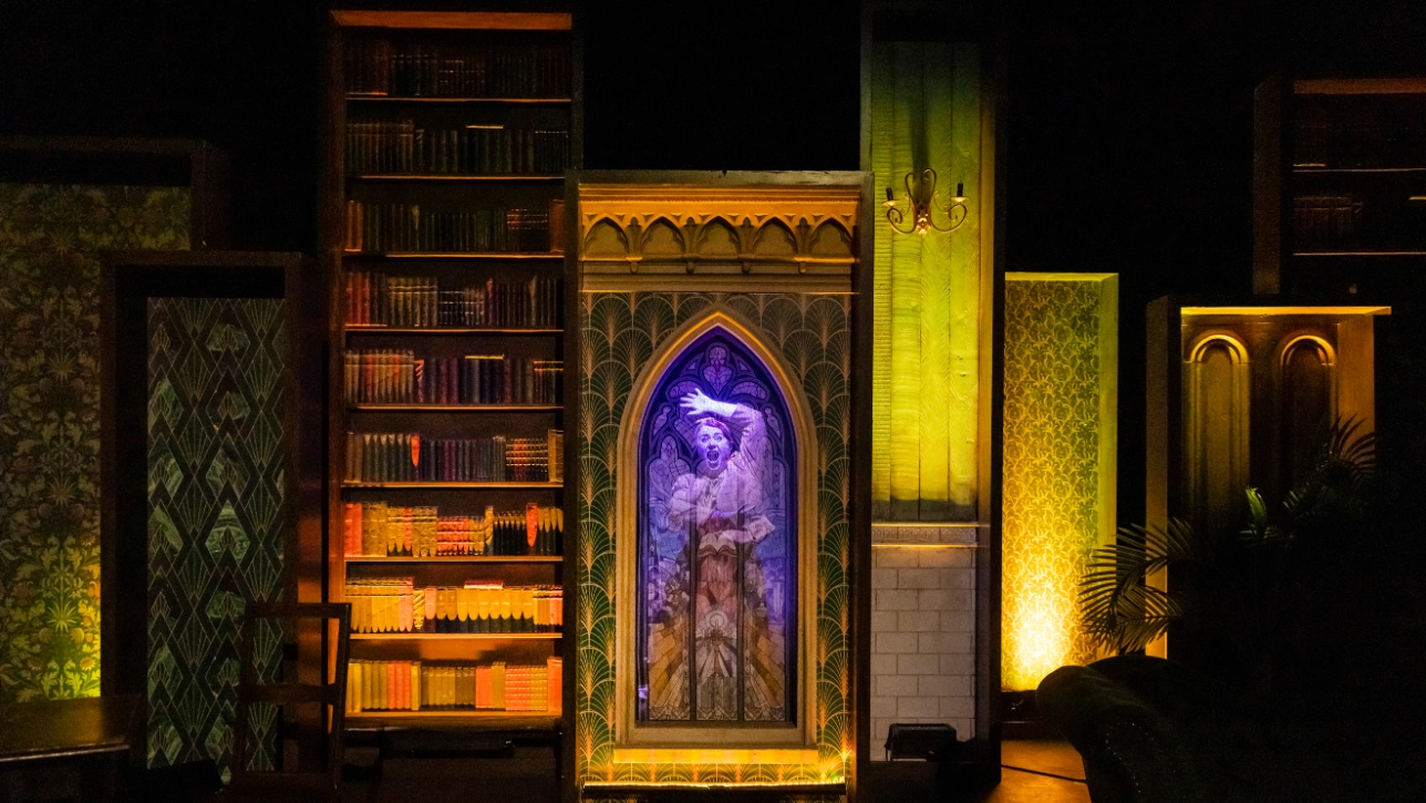 Two actors hold a pose set in a library on stage 