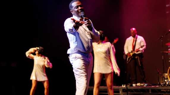 Male Motown performer reaching out toward the camera on stage