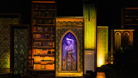 Two actors hold a pose set in a library on stage 
